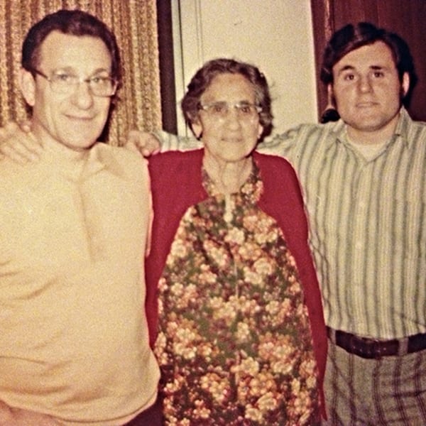 Three generations of the Cortina family, two men and a woman, smiling for a photo.