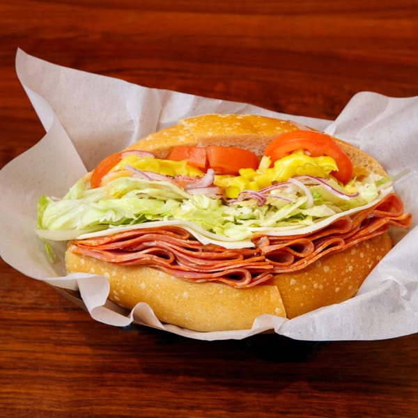 A Cortina's Italian Market & Pizzeria sandwich with salami, cheese, lettuce, tomatoes, and onions.