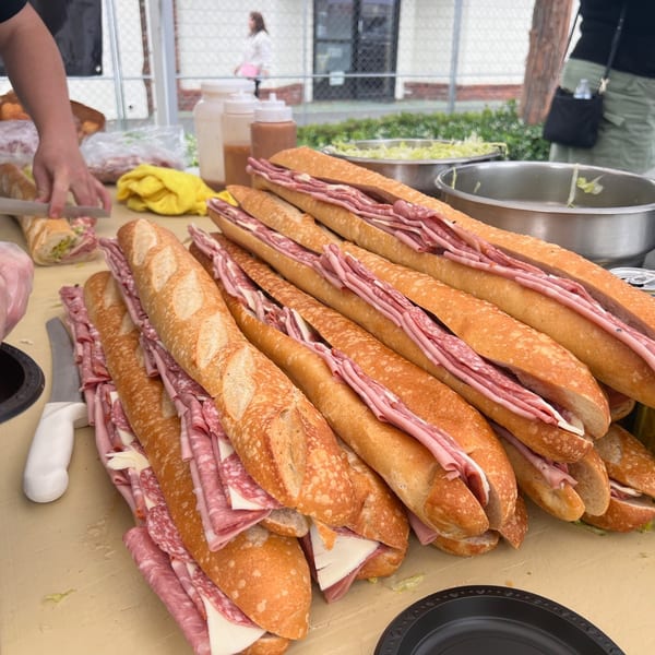 Many large Italian subs with various meats and cheese on a table at Cortina's.