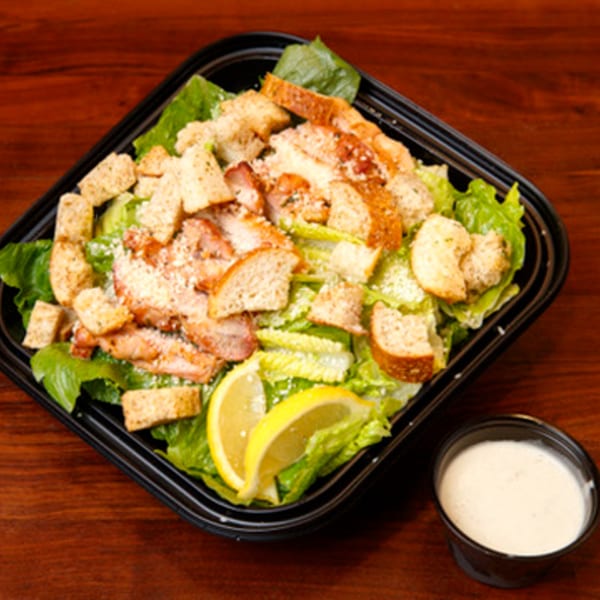 Cortina's Italian Market & Pizzeria's Caesar salad with chicken, croutons, parmesan, and lemon wedges.