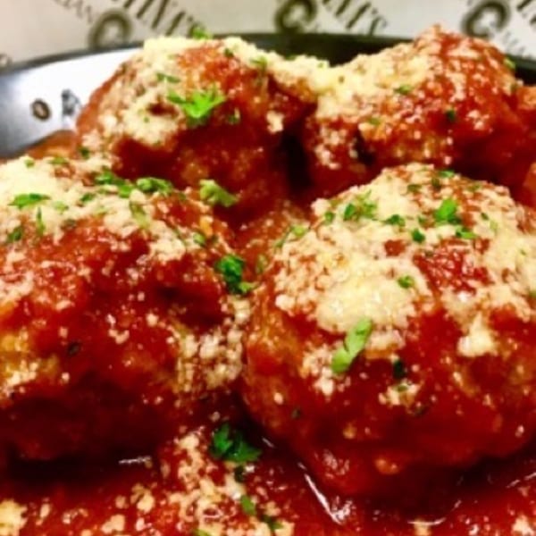Close-up of Cortina's Italian Market & Pizzeria's meatballs covered in red sauce, parmesan, and parsley.