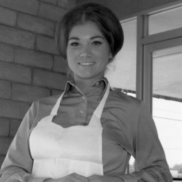 Black and white photo of a smiling woman in an apron, likely a Cortina's employee.
