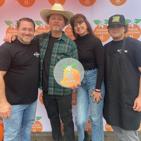 Four people, two men and two women, pose with a "2025 Best Taste of Orange" award.