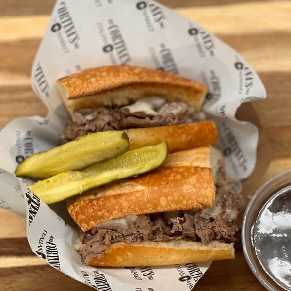Cortina's Italian Market & Pizzeria's Italian beef sandwich with melted cheese and pickles, served with au jus.