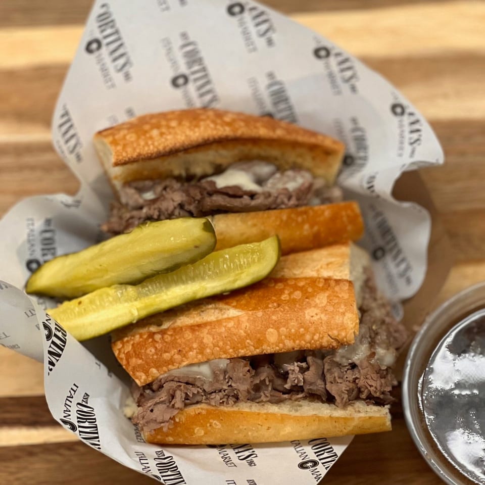 Cortina's Italian Market & Pizzeria's Italian beef sandwich with melted cheese and pickles, served with au jus.