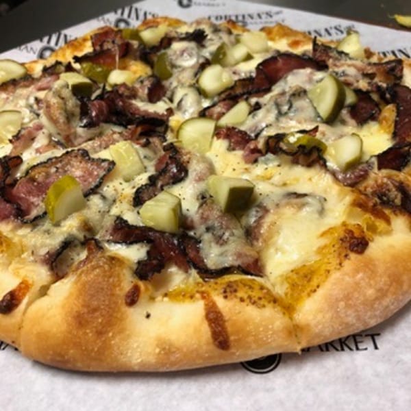 Close-up of a Cortina's Italian Market & Pizzeria pizza with pastrami, cheese, and pickles.