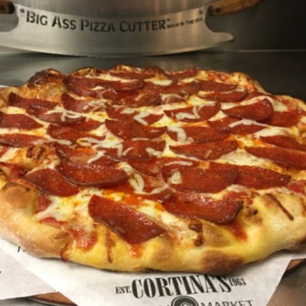 A large pepperoni pizza from Cortina's Italian Market, with a "Big Ass Pizza Cutter" in the background.