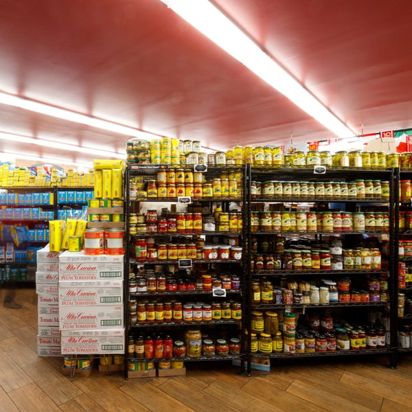 Shelves filled with various Italian market products, including canned tomatoes, jarred olives, and pasta.