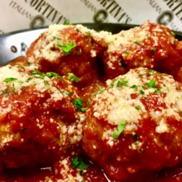 Close-up of Cortina's Italian Market & Pizzeria meatballs in red sauce, topped with Parmesan and parsley.